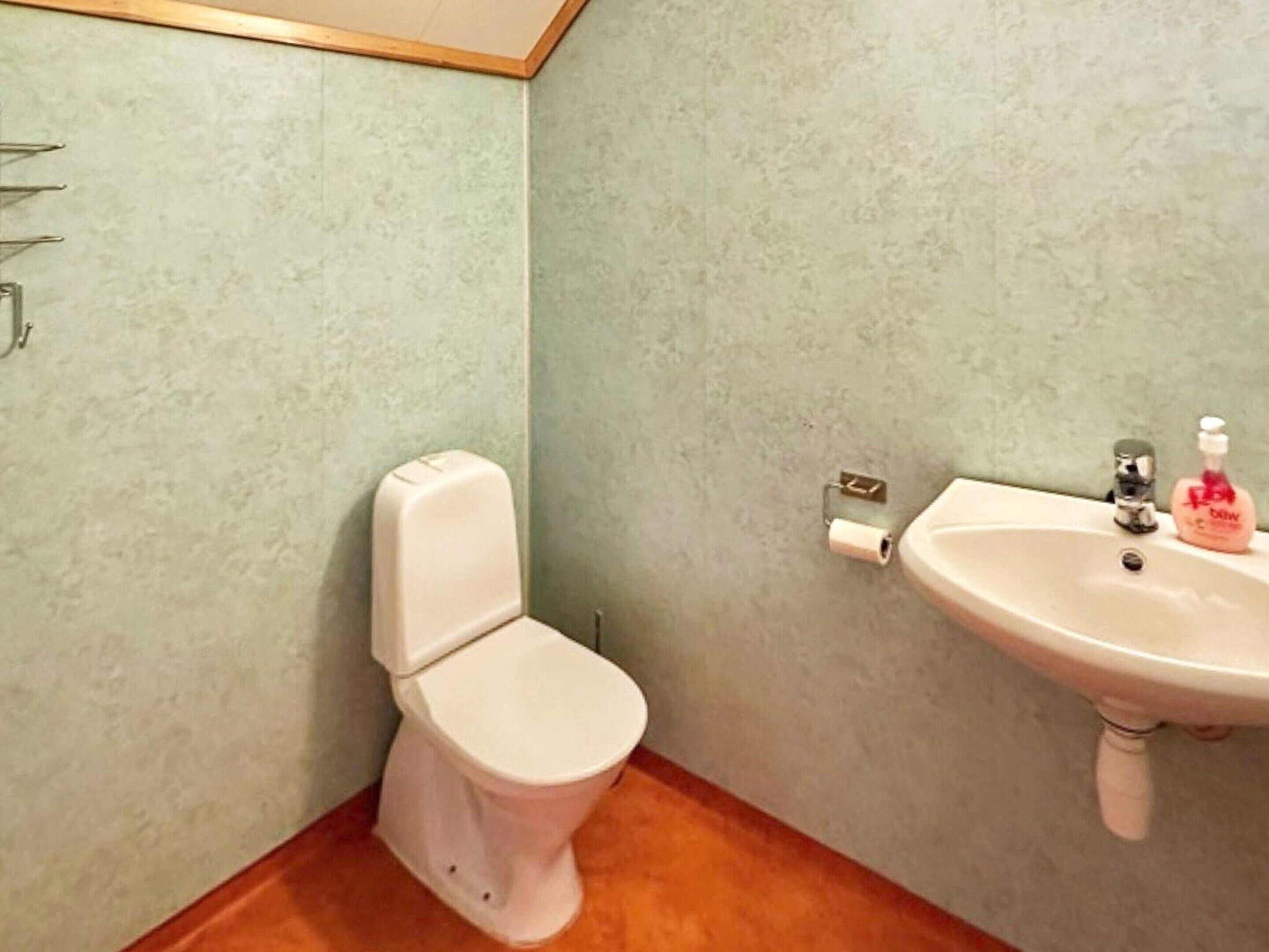 A bathroom with a toilet, a sink, and a toilet paper holder.