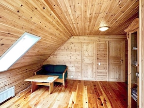 A wooden interior with a sloped ceiling, a sofa, a table, and built-in cabinets. - 6 Person Holiday Home in Gudvangen (Aurland)