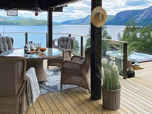 A deck with wicker furniture, a glass table, and a view of a lake and mountains. - 10 Person Holiday Home in Treungen-by Traum (Nissedal)