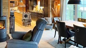A cozy cabin interior with a fireplace, wooden furniture, and a large window offering a view of the outdoors. - 10 Person Holiday Home in Treungen-by Traum (Nissedal)