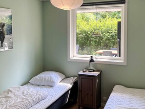 A bedroom with two beds, a window with a view of greenery, a bedside table with a lamp, and a cabinet. - 6 Person Holiday Home in Albaek (Aalbaek)