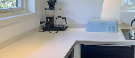 Une cuisine équipée d’une machine à café, d’un garde-pain et d’une bouilloire posés sur le plan de travail.