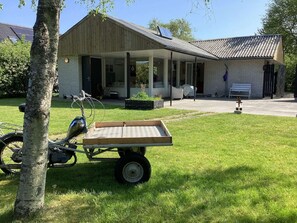 A house with a covered porch, a solar panel on the roof, and a bicycle with a cart. - 6 Person Holiday Home in Albaek (Aalbaek)