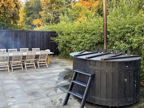 A wooden hot tub with a ladder, a table with chairs, and a wooden fence in a garden setting. - 6 Person Holiday Home in Albaek (Aalbaek)