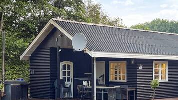A log cabin with a porch, outdoor seating, and a satellite dish.