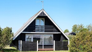 A black wooden house with a triangular roof, a balcony, and a small porch. - 6 Person Holiday Home in Hadsund (Hadsund)