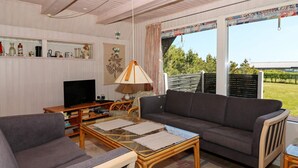 A living room with a sofa, armchair, coffee table, TV, and a bookshelf. - 6 Person Holiday Home in Hadsund (Hadsund)