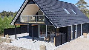 A modern house with a sloped roof, large windows, and a covered outdoor seating area. - 6 Person Holiday Home in Laeso-by Traum (Læsø)