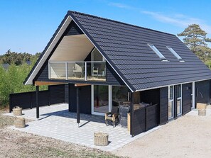 A modern house with a sloped roof, large windows, and a covered outdoor seating area. - 6 Person Holiday Home in Laeso-by Traum (Læsø)