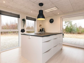 A modern kitchen with a central island, large windows, and a view of the outdoors. - 6 Person Holiday Home in Laeso-by Traum (Læsø)
