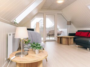 Un dormitorio estilo loft moderno con tragaluces, una mesa redonda de madera con una lámpara, un sofá y una silla.