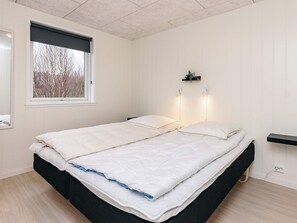 Un dormitorio con una cama, un ventanal con vistas y dos lámparas de pared.
