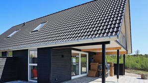 A modern house with a tiled roof, a covered patio, and a large glass door. - 6 Person Holiday Home in Laeso-by Traum (Læsø)