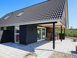 A modern house with a tiled roof, a covered patio, and a large glass door. - 6 Person Holiday Home in Laeso-by Traum (Læsø)