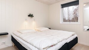 A bedroom with a bed, bedside lamps, a window, and a wall-mounted plant. - 6 Person Holiday Home in Laeso-by Traum (Læsø)