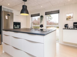 Una cocina moderna con una isla central, electrodomésticos de acero inoxidable y una planta colgante.