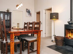 A cozy dining area with a wooden table and chairs, a wall-mounted clock, a framed floral artwork, and a standing lamp. - 5 Person Holiday Home in Bording (Bording)