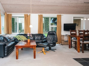 Una sala moderna con un sofá de cuero, una mesa de centro de madera y una zona de comedor con sillas de madera.