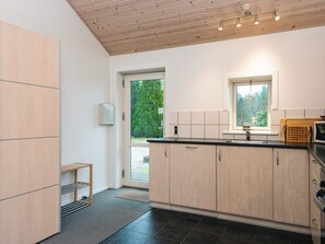 A modern kitchen with wooden cabinets, a black countertop, and a window providing natural light.