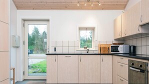A modern kitchen with light wood cabinets, a black countertop, and a window above the sink. - 5 Person Holiday Home in Bording (Bording)