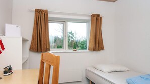 A small, tidy room with a single bed, a wooden chair, a desk with a small figurine, and a window with curtains. - 5 Person Holiday Home in Bording (Bording)