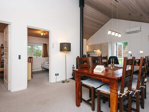 A dining area with a wooden table and chairs, a floor lamp, and a view into the kitchen.