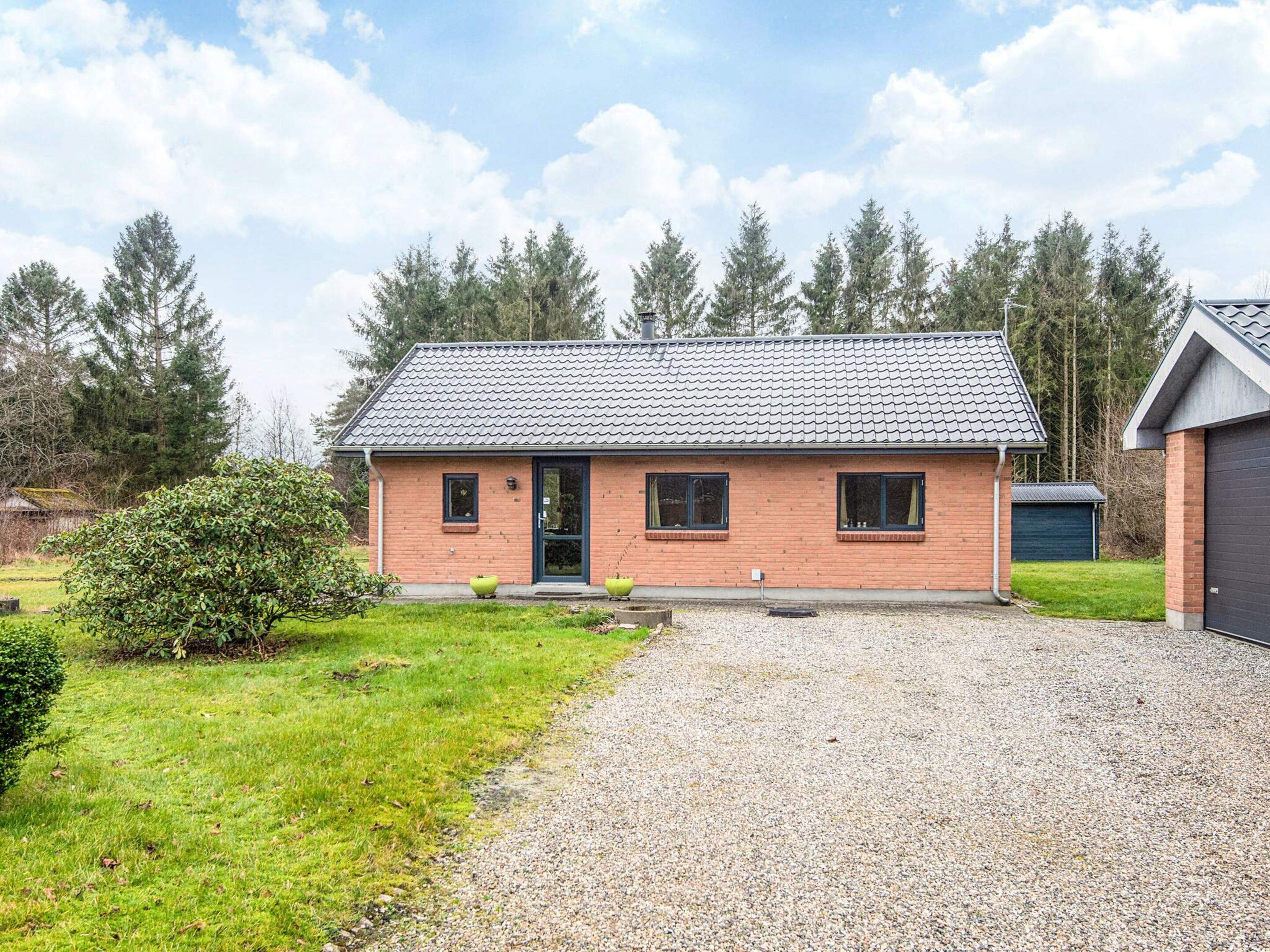 Ein einstöckiges Haus mit Ziegeldach, Backsteinfassade und einem Schotterweg.