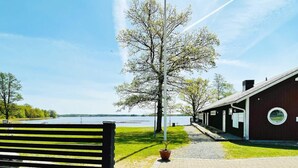 A bench overlooking a lake, a wooden building with a circular window, and a paved walkway. - 6 Person Holiday Home in Tingsryd-by Traum (Tingsryd)