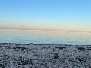 Une plage avec un ciel dégagé et une eau calme.