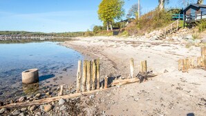 Une plage avec des poteaux en bois, une structure en béton et un bâtiment doté d’une terrasse.