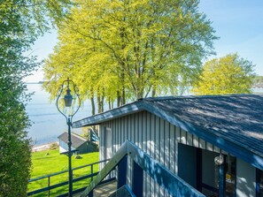 A building with a blue roof, a staircase, and a view of a lake. - 6 Person Holiday Home in Bjert (Bjert)