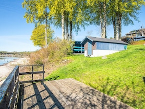 A wooden deck leading to a building with a metal roof, surrounded by grass and trees. - 6 Person Holiday Home in Bjert (Bjert)