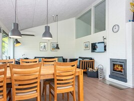 Una sala de estar moderna con chimenea, muebles de madera y ventanas amplias.