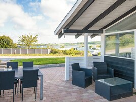En udendørs terrasse med overdækket siddeområde, et bord og stole.