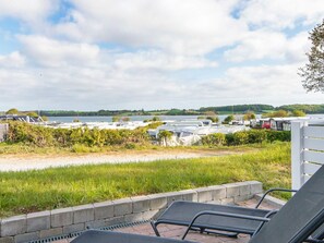 A view of a lakeside camping area with RVs parked along the shore, a grassy area in the foreground, and a clear sky. - 5 Person Holiday Home in Aabenraa (Aabenraa)