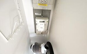 A narrow corridor with a white wall and a door at the end.