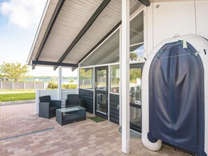 Una terrazza esterna con zona salotto coperta, un barbecue e un serbatoio d'acqua di grandi dimensioni.