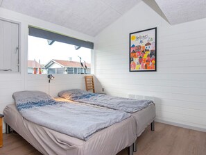 Una camera da letto con un letto, una finestra, una sedia e una parete decorata con un quadro colorato.
