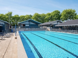 A swimming pool with clear blue water, surrounded by lounge chairs and covered seating areas.