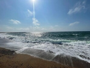 A beach with waves and a clear sky.