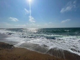 A beach with waves and a clear sky.