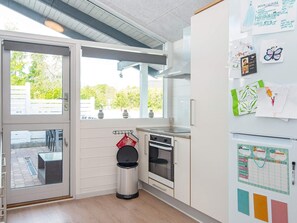A modern kitchen with a built-in oven, a stainless steel trash bin, and a refrigerator with papers and magnets. - 5 Person Holiday Home in Aabenraa (Aabenraa)
