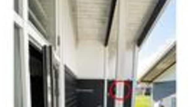 Área externa coberta com porta, um poste de metal e um caminho de tijolos.