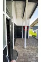 Un espacio al aire libre cubierto con una puerta, un poste metálico y un camino de ladrillos.