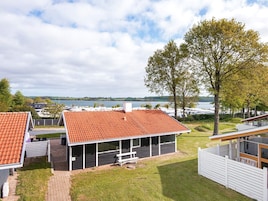 A modern building with a red-tiled roof, a covered patio, and a view of a lake.