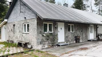A stone building with a metal roof, a front porch, and a small outdoor seating area.