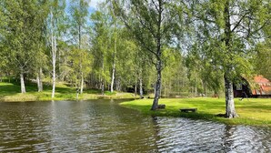 A serene park with a pond, trees, and a bench. - 7 Person Holiday Home in Klassbol (Klässbol)