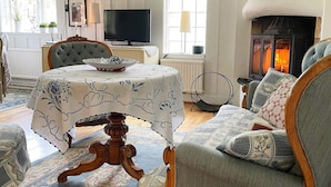 A cozy living room with a fireplace, a television, and a dining area with a table set for four. - 7 Person Holiday Home in Klassbol (Klässbol)