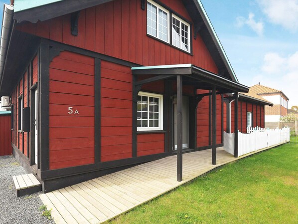 A red building with a number '5A' on the side, a covered porch, and a white fence in the background.
