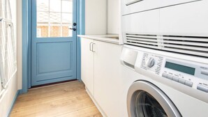 A laundry room with a blue door, a washing machine, and a drying rack. - 10 Person Holiday Home in Marstal (Marstal)